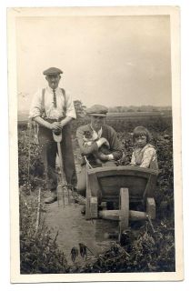   IN FIELD W HIS SON DAUGHTER & THEIR CAT IN OLD WOODEN WHEELBARROW